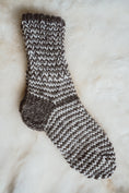 Load image into Gallery viewer, Pair of black and white ladies' wool socks placed on a cozy sheepskin rug.