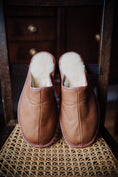 Load image into Gallery viewer, Soft men's leather slippers with cream wool lining, elegantly displayed on a nice chair.