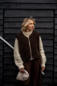 Load image into Gallery viewer, Woman wearing a Freya merino wool vest in espresso brown over a cream knit jumper.
