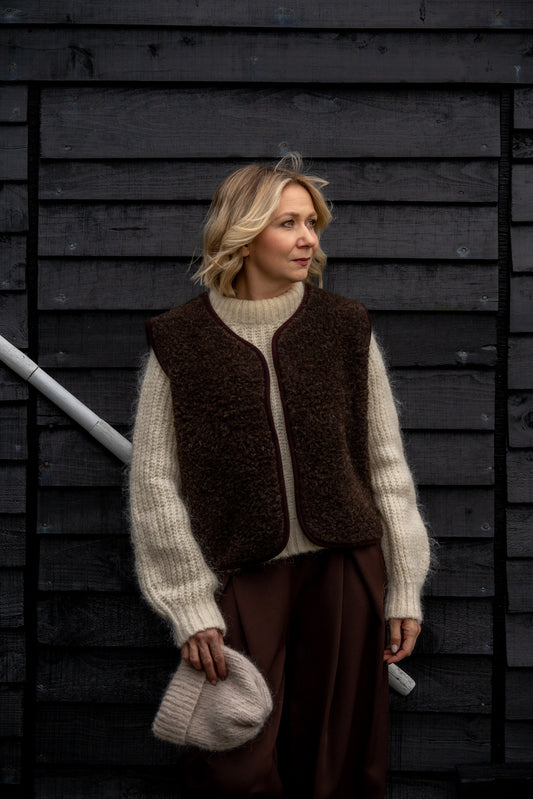 Woman wearing a Freya merino wool vest in espresso brown over a cream knit jumper.