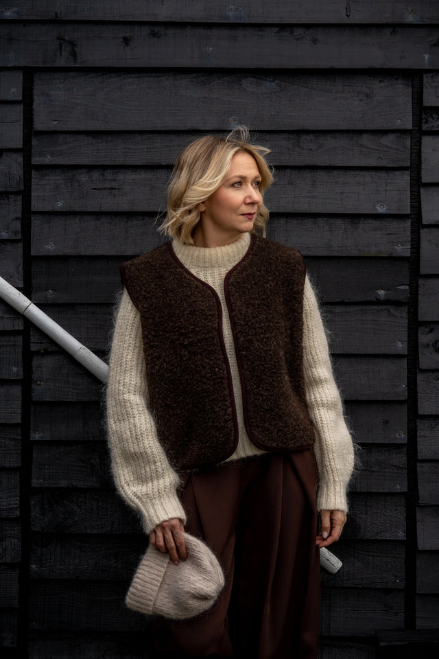 Woman wearing a Freya merino wool vest in espresso brown over a cream knit jumper.