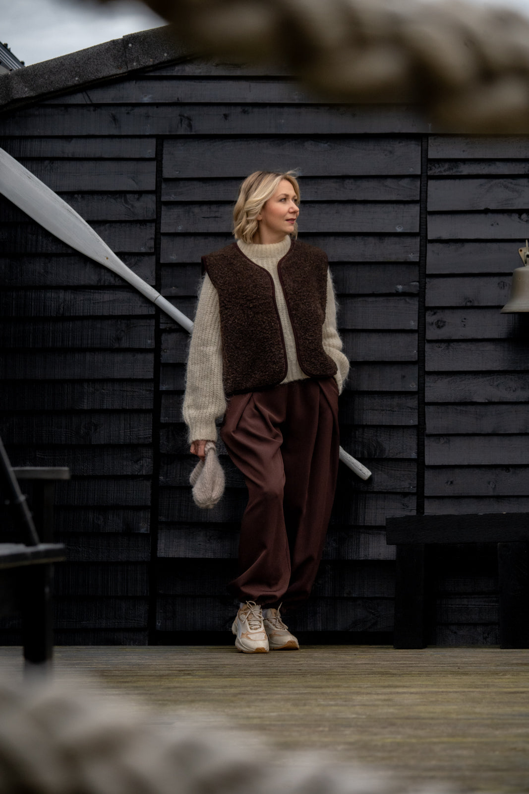 Full-length outfit featuring the Freya espresso merino wool vest, styled with neutral knitwear and brown trousers.
