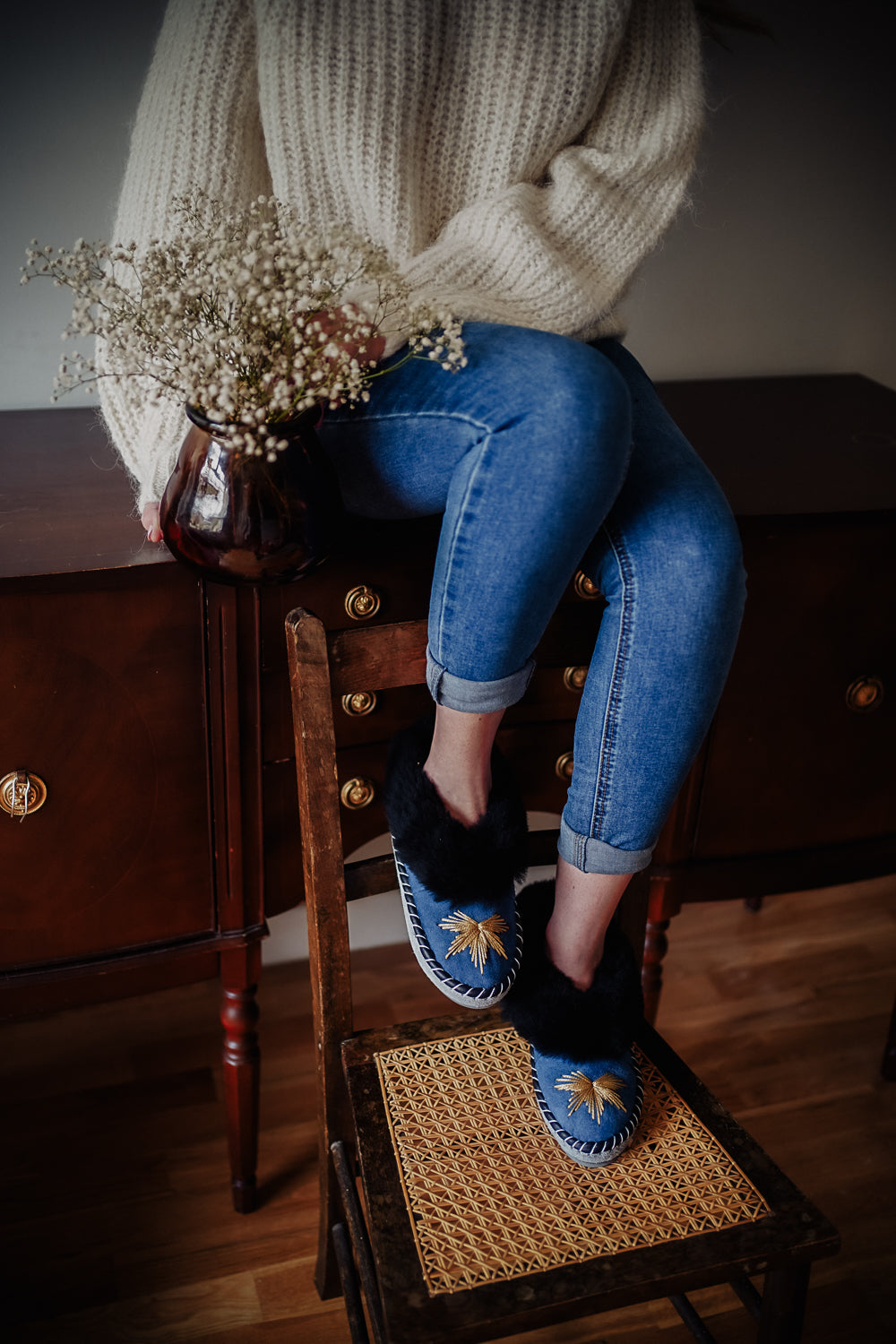 Blue jeans color leather slippers with golden thread embroidery and black sheepskin cuff or fur. Stylish woman fashion footwear