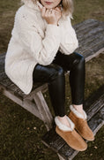 Load image into Gallery viewer, Woman wearing caramel leather boots with rubber sole and woollen lining. She feel warm and comfortable and stylish.
