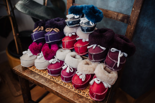 red colour Sheepskin booties or indoor shoes on the chair. Perfect gift idea for baby shower party