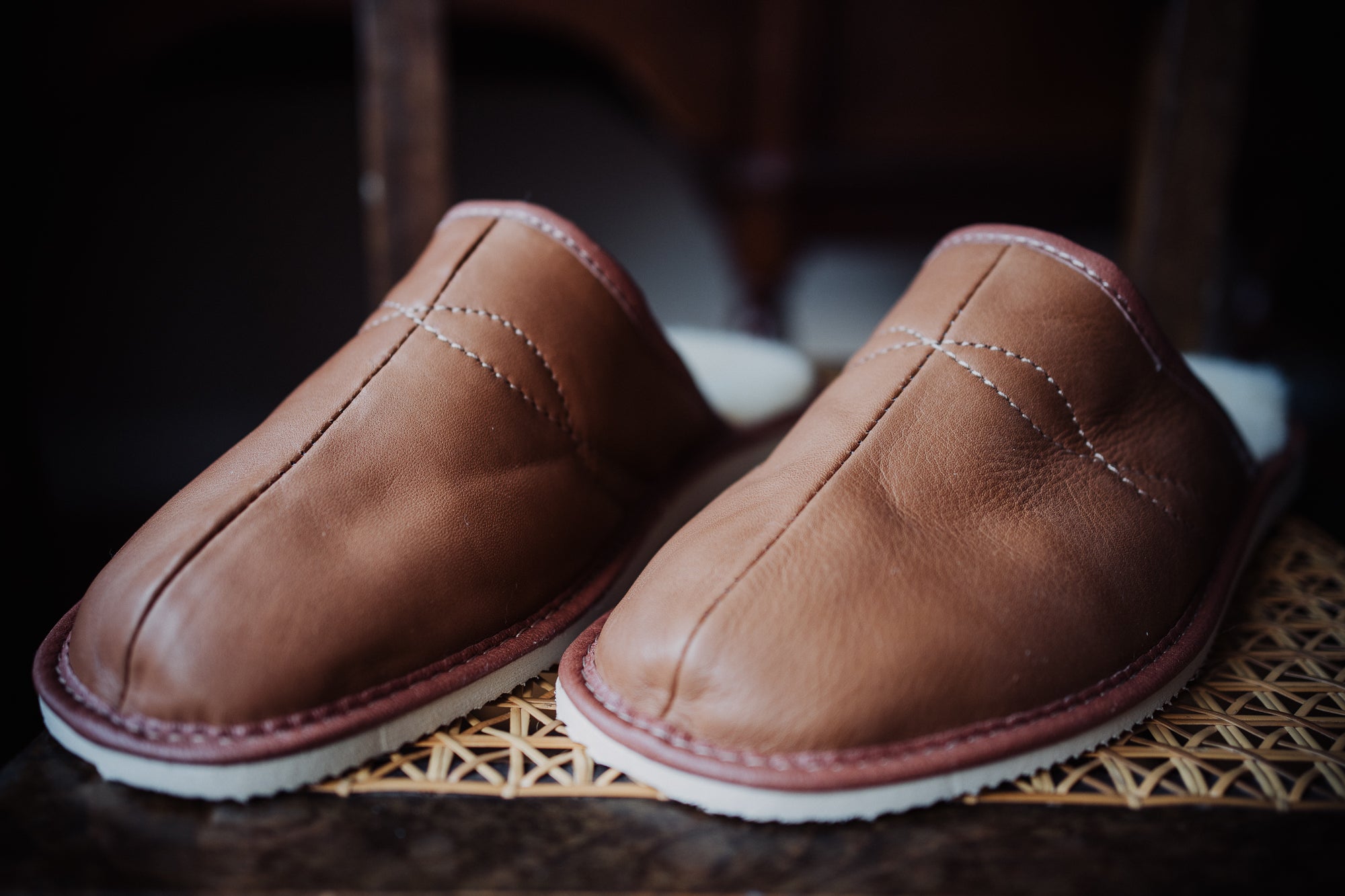 High quality men's slippers featuring soft leather and cozy wool lining, showcased on a stylish chair.