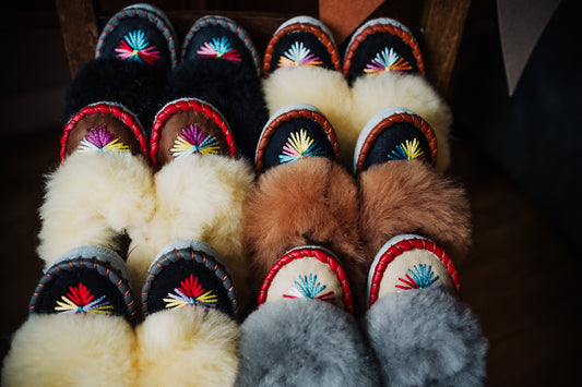 Assortment of kids' fluffy sheepskin slippers in various vibrant colors, adorned with beautiful and colorful embroidery.