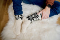 Load image into Gallery viewer, Man in woollen turtleneck and woollen cream star patterned knitted socks sitting on natural sheepskin rug. Men is feeling warm and cosy on winter time
