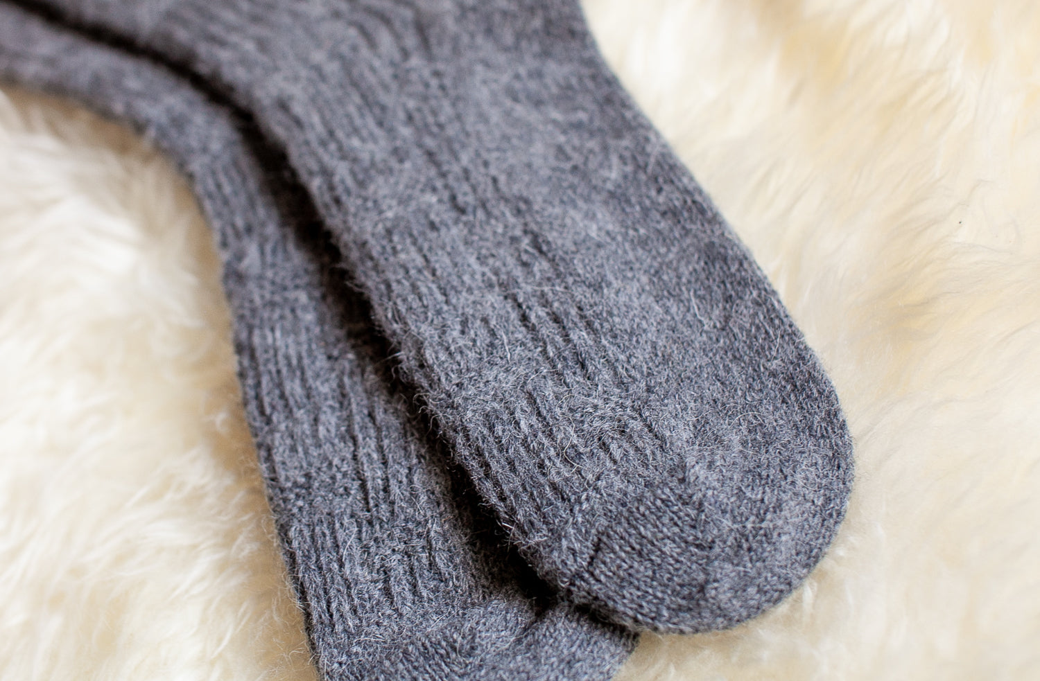 Mens woollen socks in grey colour Laying on soft Sheepskin rug