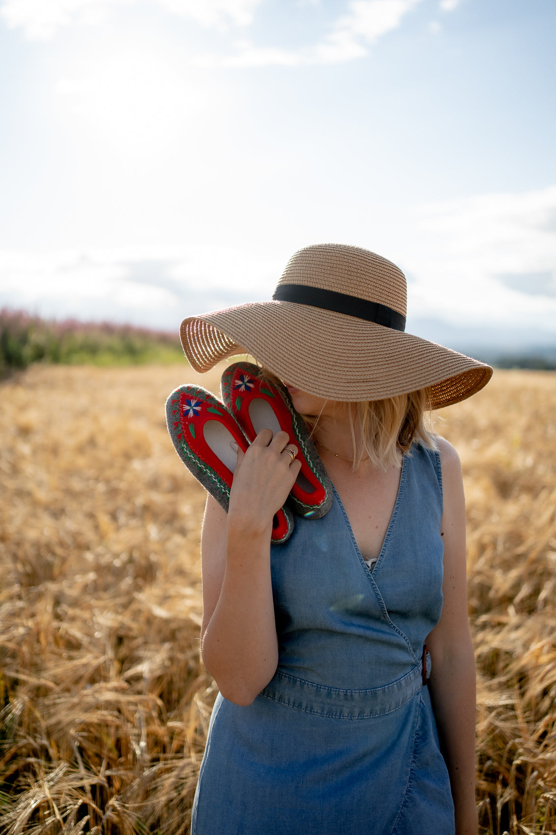 boho Woman in the middle of field holding her favourite folk, boho handmade felt woollen slippers