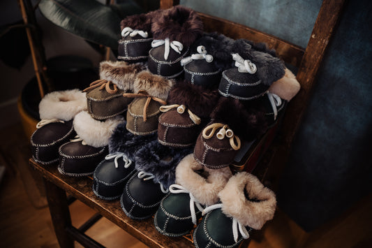 Collection of handmade baby sheepskin booties in various shades of brown.
