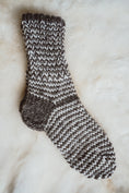 Load image into Gallery viewer, Pair of black and white ladies' wool socks placed on a cozy sheepskin rug.
