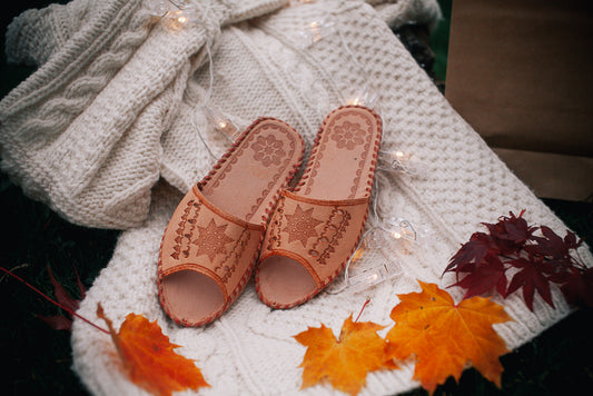 Leather slip on sandals with star element displayed on wool jumper with autumn leaves